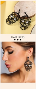 Detail of gothic skull earrings with rhinestones and star stud worn by a model