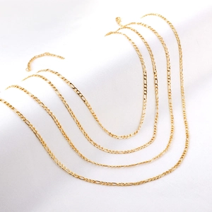 Detail view of layered gold-finished stainless steel Figaro chains with extension clasps