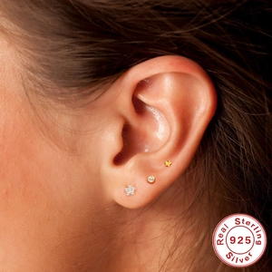 Macro view of S925 sterling silver star and flower stud earrings worn on the ear
