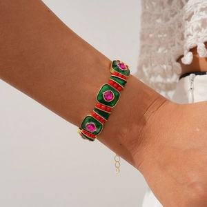 Vue macro d'un bracelet vintage doré avec émail vert et pierres précieuses roses
