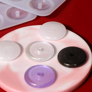 Silicone mold with various resin craft samples like pearl white and purple glitter pendants
