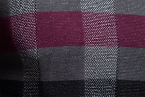 Détail du tissu en maille pour pull homme avec motif à carreaux bordeaux et gris de haute qualité