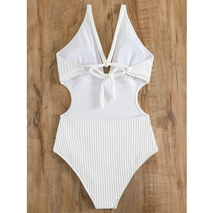 White ribbed one-piece swimsuit with V-neck cutout and lace-up back on wood background