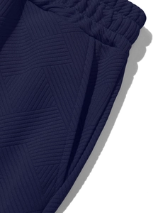 Gros plan du pantalon bleu marine montrant la taille élastique et la texture gaufrée
