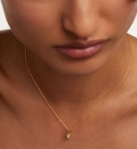 Close-up of heart-shaped lock pendant with zircon on a gold necklace worn by a model