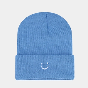 Detailed view of blue knitted beanie featuring a white embroidered smile on the ribbed cuff