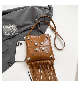 Close-up of brown PU leather crossbody bag with silver rivets and long tassel fringe