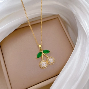 Macro detail of cherry pendant with green gems and zircon inlay on a soft beige background