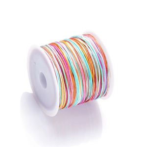 Macro detail of rainbow gradient braided cord wrapped on a white spool for DIY jewelry