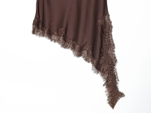 Detail of dark brown satin skirt hem featuring delicate eyelash lace and asymmetrical cut