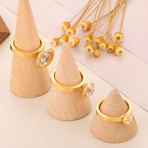 Trois bagues multicouches dorées avec zircones sur des supports à bijoux en bois
