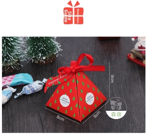 Macro view of pyramid Christmas gift box with festive patterns and red ribbon tie