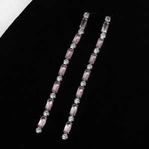 Macro view of elegant pink and white zircon tassel earrings on black velvet backdrop