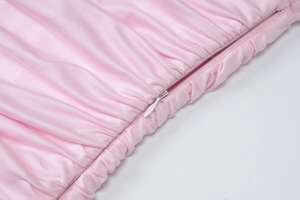 Dettaglio della cerniera invisibile su abito estivo rosa a pieghe in tessuto satin