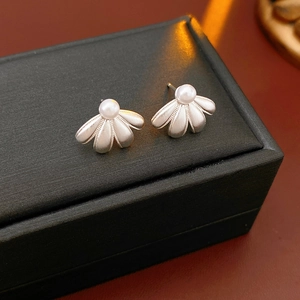 Detailed shot of silver shell-shaped pearl earrings on a black jewelry gift box