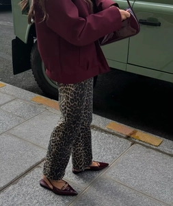 Close-up of leopard print straight-leg trousers paired with a burgundy cropped jacket