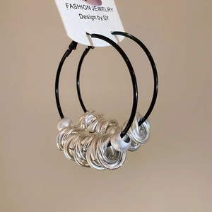 Detail shot of black hoop earrings with silver beaded metal rings on white display card