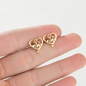 Golden hollow heart-shaped stud earrings with musical note design held in hand
