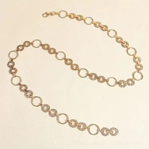 Detail of golden chain belt featuring hollow rings and textured discs with lobster clasp