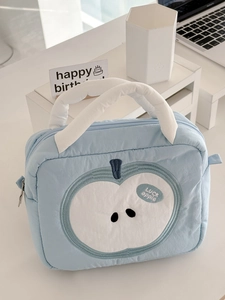 Close-up of quilted light blue makeup bag with white apple embroidery and padded handle