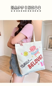 Detail of white canvas tote bag featuring cute pink pig and yellow chick cartoon prints