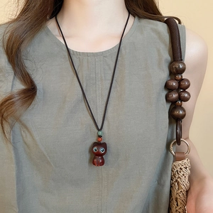 Detail of cute cat pendant necklace with green eyes on woven cord worn by model