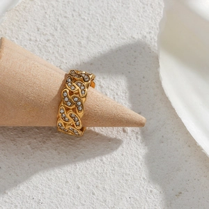 Close-up of a gold Cuban chain ring with clear zircons on a wooden display stand