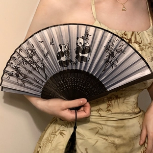 Classic Chinese folding fan with ink panda and bamboo patterns, held by a model