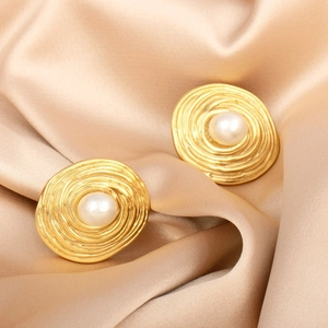 Close-up of vintage gold spiral textured earrings with white faux pearl on silk