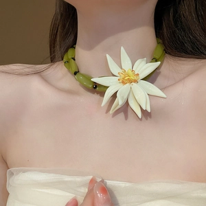 Detail of a resin green bead necklace with a large 3D white flower and yellow center