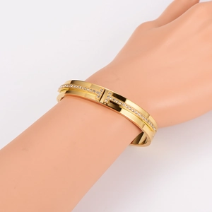 Luxurious gold stainless steel H-clasp bangle with sparkling pavé crystals on a model's hand
