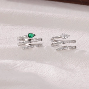 Modern spiral snake ring with pear-cut green and white crystals on textured fabric