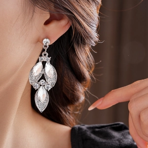 Close-up of sparkling diamond flower earrings with marquise crystals on a female model