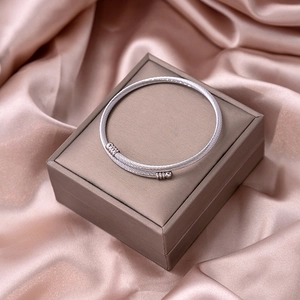 Close-up of silver twisted metal cuff bracelet on dark jewelry box with pink silk