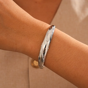 Detail of 18k gold plated bangle with twill design and shimmering cubic zirconia stones