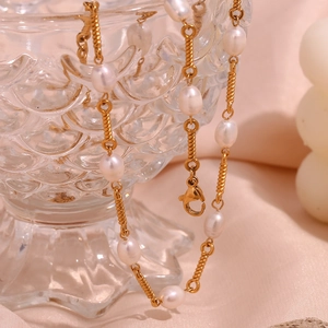 Detail of 18K gold-plated twisted metal chain necklace with freshwater pearls on glass