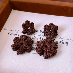 Detail of coffee brown hand-woven raffia flower earrings with intricate braided texture
