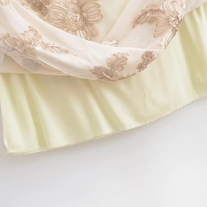 Macro détaillée de broderies florales élégantes sur tissu en maille beige pour robe longue