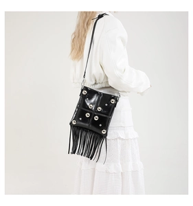 Detail of a vintage black fringe bag featuring silver studs and long tassels on a crossbody strap