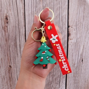 Handheld view of a 3D green Christmas tree PVC keychain with red silicone wristband strap