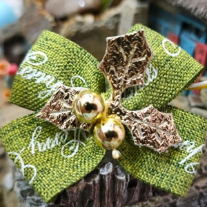 Grüne Leinenschleife für Weihnachten mit weißem Schriftzug und goldenem Stechpalmen-Detail