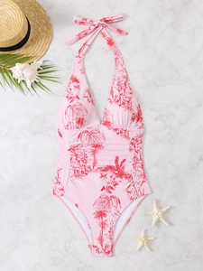 Flat lay of pink halter neck swimsuit with tropical red floral print and beach props