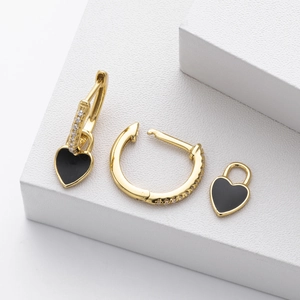 Detailed macro view of gold heart lock earrings with black enamel and white zircon accents