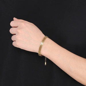 Gros plan d'un bracelet gourmette tressé doré montrant les détails de la maille au poignet