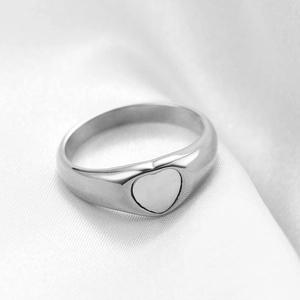 Detailed view of heart-shaped signet ring with polished silver finish on silk fabric