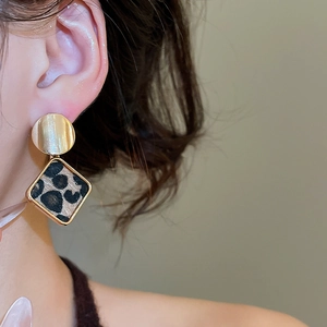 Detail of vintage leopard print geometric earrings in gold finish on female model