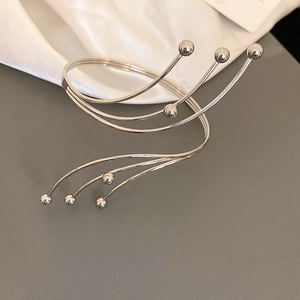 Vista detallada del brazalete plateado ondulado de cinco capas con puntas de esfera