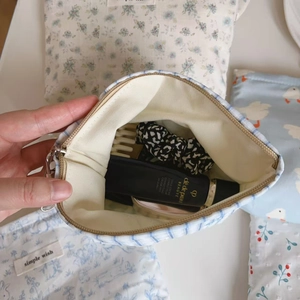Blue and white striped cotton bag interior view with cosmetics and pearl chain detail