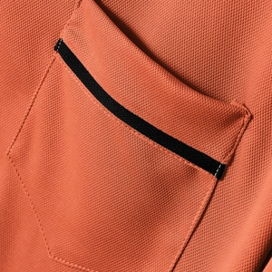 Details des atmungsaktiven orangefarbenen Wabenstrickstoffs mit schwarzen Taschenakzenten