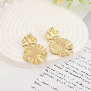Detailed view of gold liquid lava heart earrings on a white textured stone display